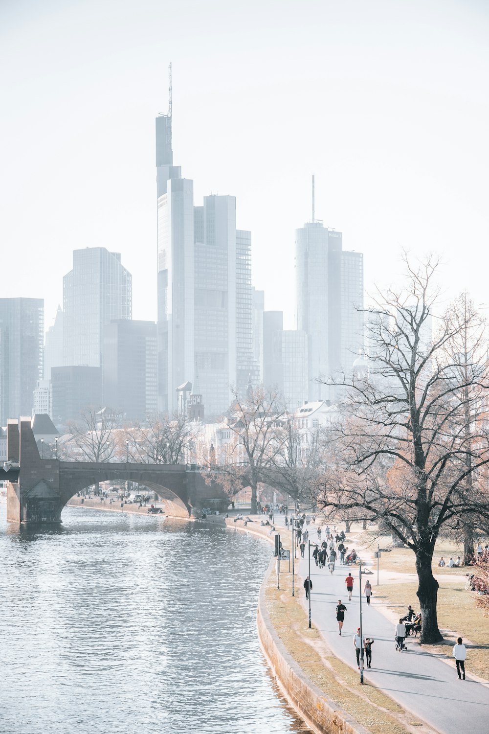 a group of people walking down a sidewalk next to a river