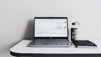 Close-up of a minimalist desk with a glowing laptop showcasing brand strategy graphs.