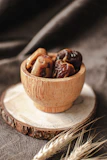 A rustic bowl filled with glossy dates and mixed nuts on a wooden table