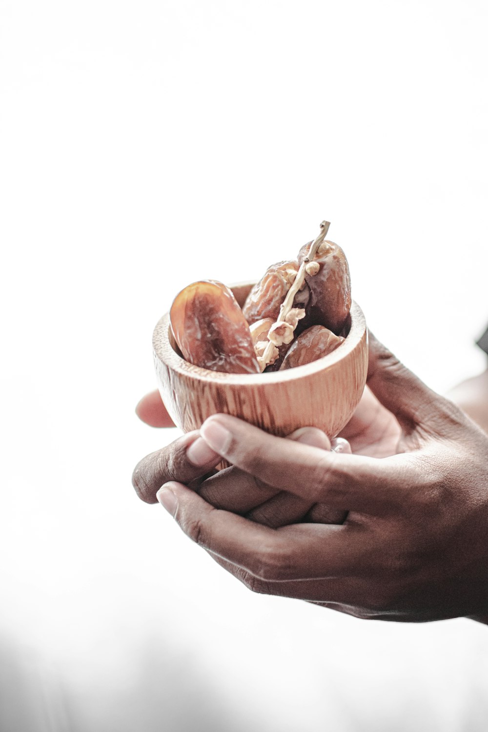 a person holding a wooden bowl filled with food