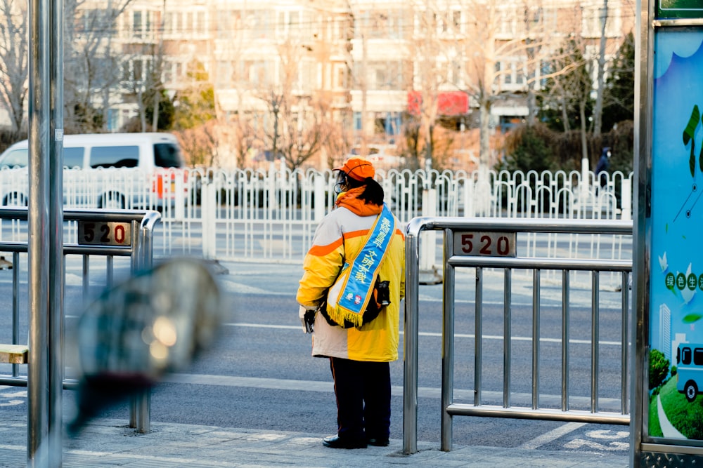 a woman in a yellow jacket stands at a bus stop