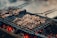 Juicy pieces of meat are sizzling on a grill, positioned over glowing charcoal embers. The scene captures the essence of a barbecue with a smoky and rustic appeal, enhanced by the visible grill marks on the meat.
