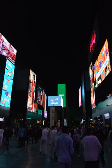 A vibrant outdoor LED screen displaying colorful advertisements on a busy street corner at dusk.