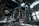 An abandoned industrial building with large, hollow structures and broken walls surrounded by rubble on the ground. Sunlight streams through the partially collapsed roof, casting dramatic shadows and highlighting the decaying architecture.