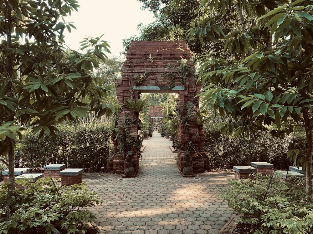 a brick archway in a garden surrounded by trees