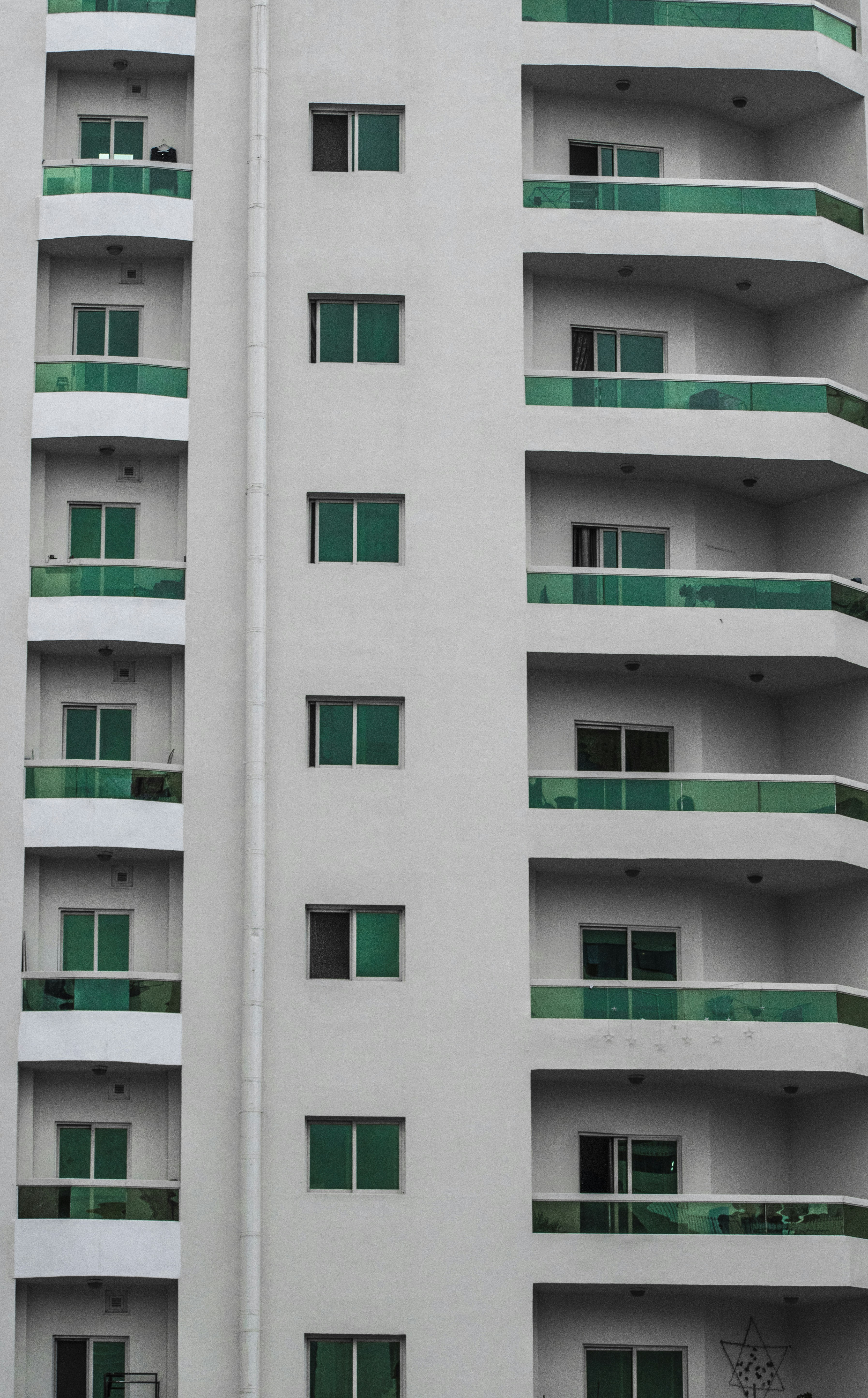 a tall white building with green balconies