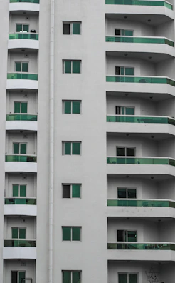 Modern residential building with dark green accents and smooth rounded balconies.