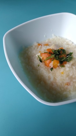 Close-up of a steaming bowl of colorful porridge topped with fruits.