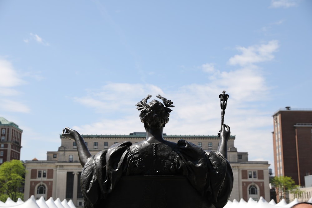 a statue of a woman holding a staff in front of a building