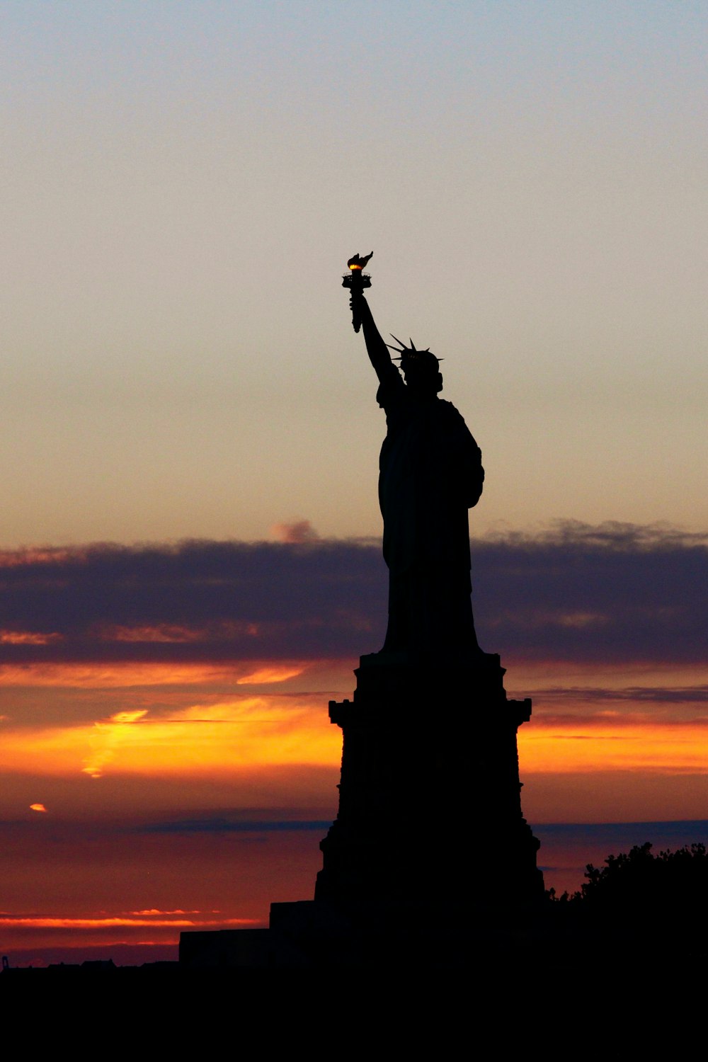 the statue of liberty is silhouetted against a sunset