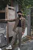 a man wearing a face mask leaning against a wall