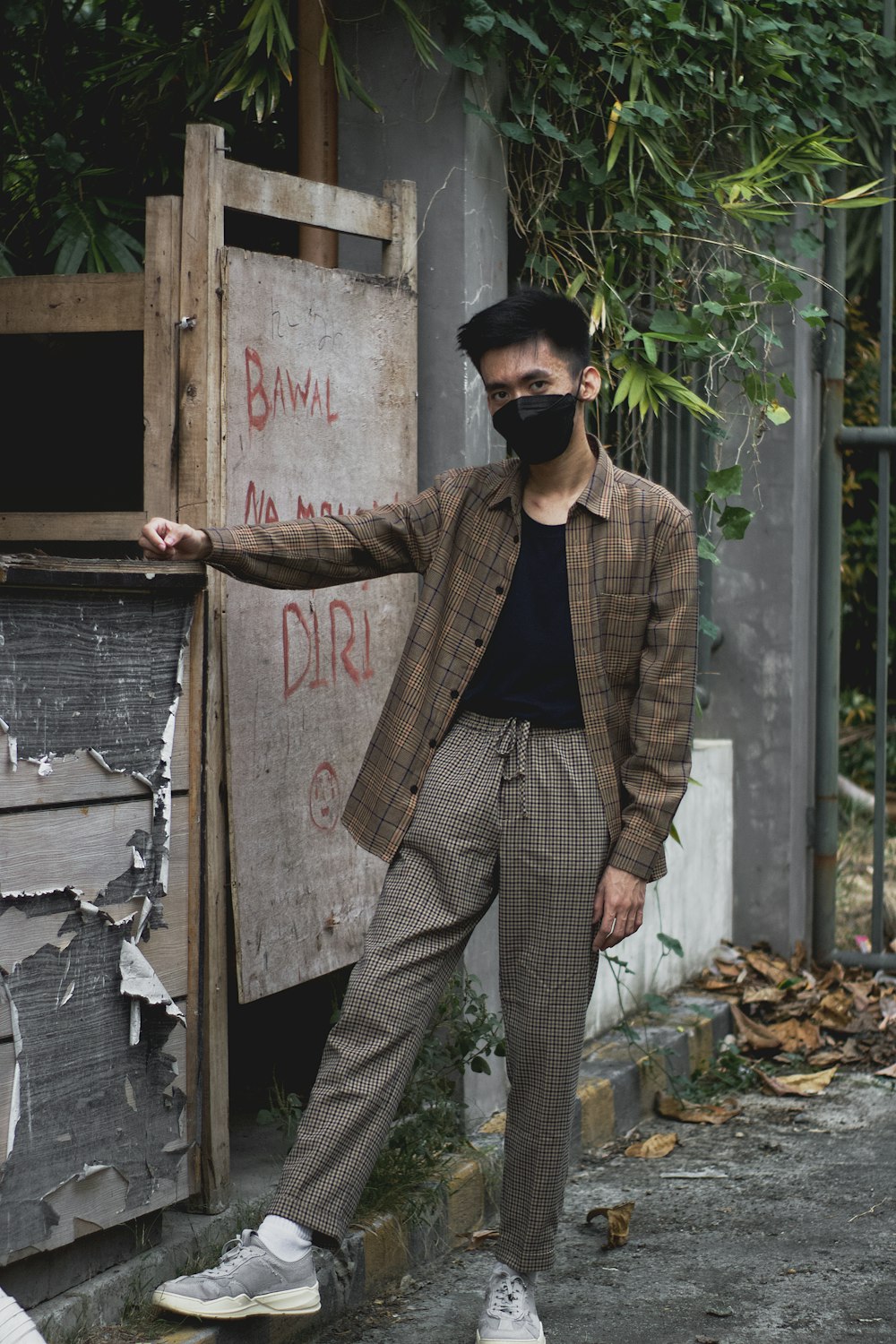 a man wearing a face mask leaning against a wall