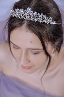 A stunning close-up of a queen wearing a shimmering crown under soft, elegant lighting.