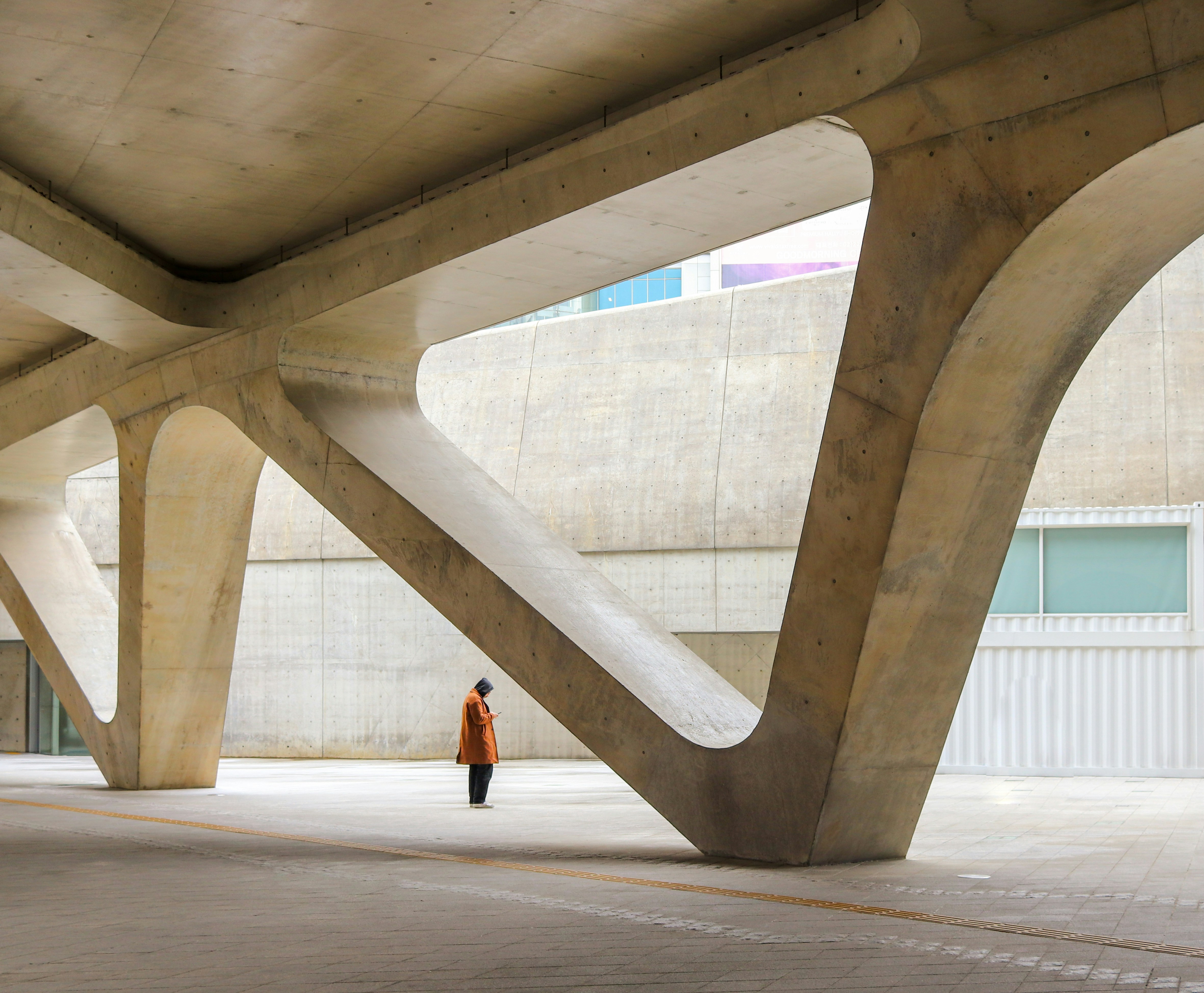 a person standing under a large structure in a parking lot, 