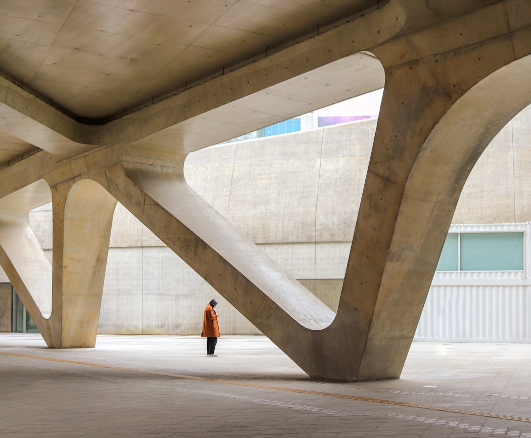 a person standing under a large structure in a parking lot,