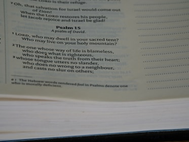 A close-up view of a page from a Bible, featuring Psalm 15 prominently. The text discusses themes of righteousness and moral behavior. The page is slightly tilted, with visible text and a notation at the bottom explaining a translation choice.