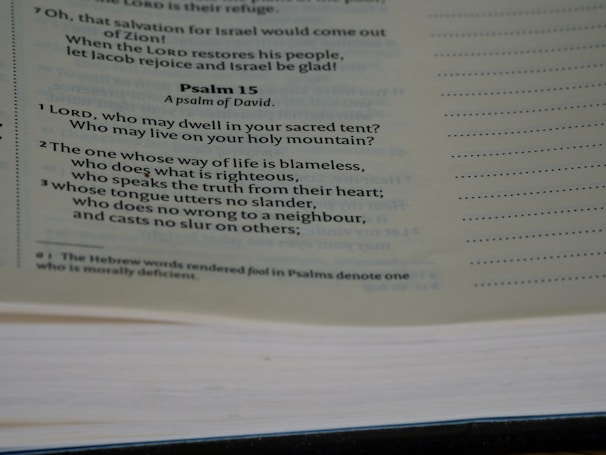 A close-up view of a page from a Bible, featuring Psalm 15 prominently. The text discusses themes of righteousness and moral behavior. The page is slightly tilted, with visible text and a notation at the bottom explaining a translation choice.