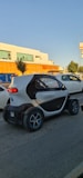 A microcar driving through a city street.