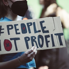 a woman holding a sign that says people not profits