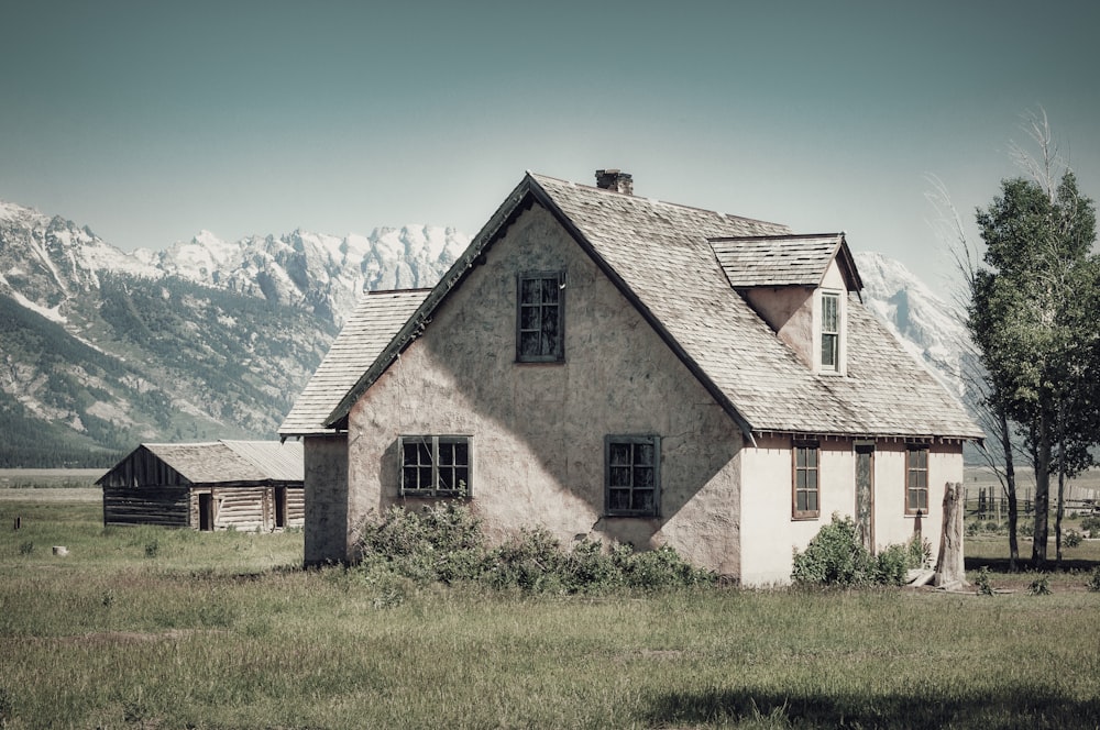 a house in a field with mountains in the background