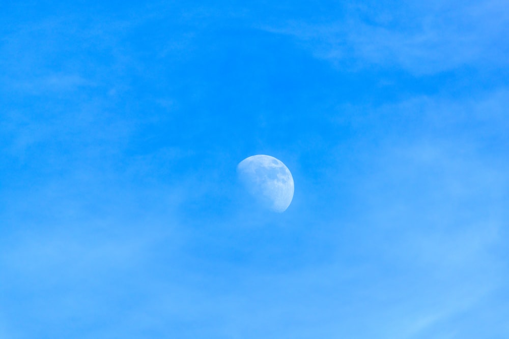 La luna está en el cielo azul con algunas nubes