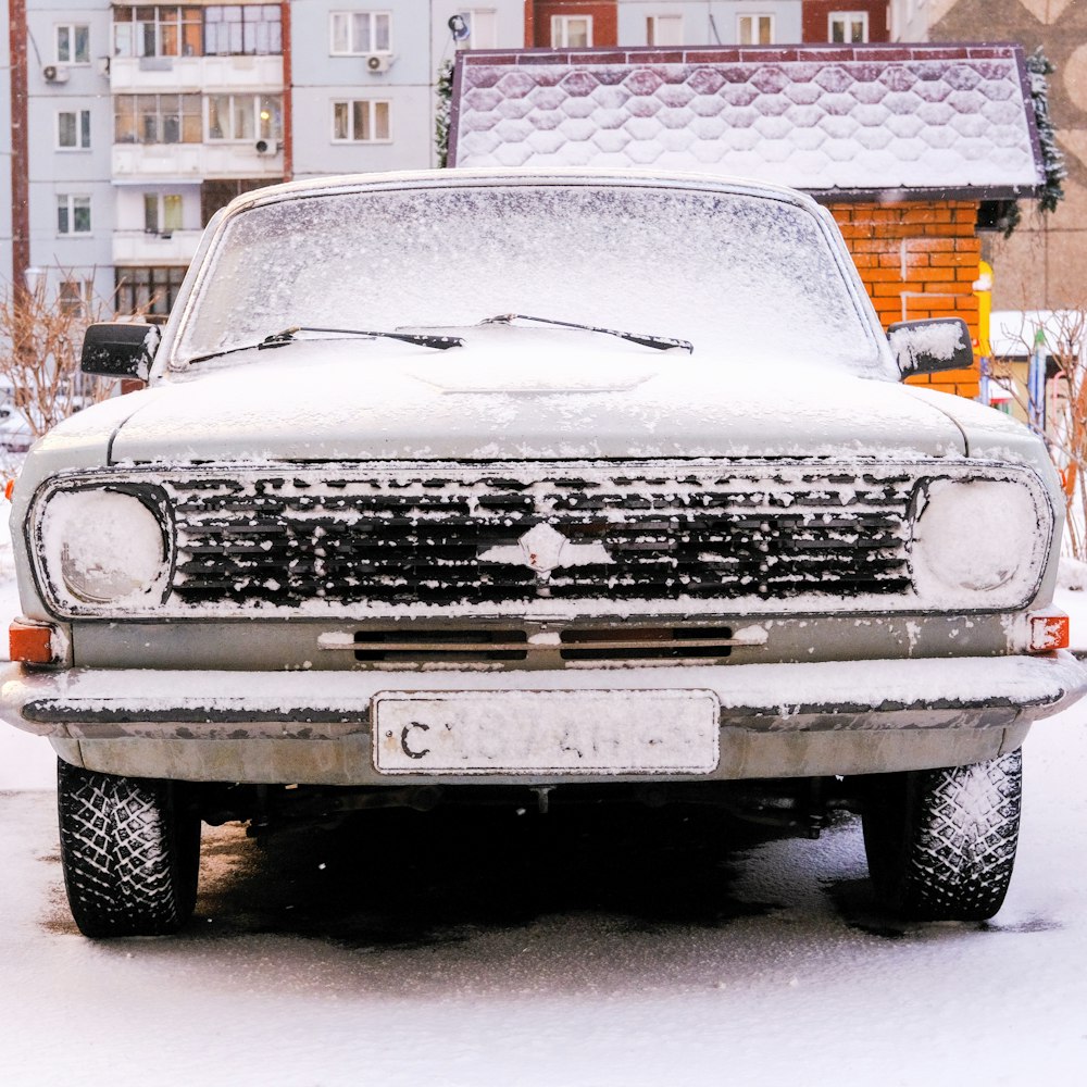 a truck is covered in snow in front of a building