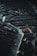 An overhead shot of a dark, intricate city model with winding streets and dense urban architecture, highlighted by sparse lighting that creates dramatic contrasts. The image conveys a sense of complexity and order within the labyrinthine arrangement of buildings and pathways.