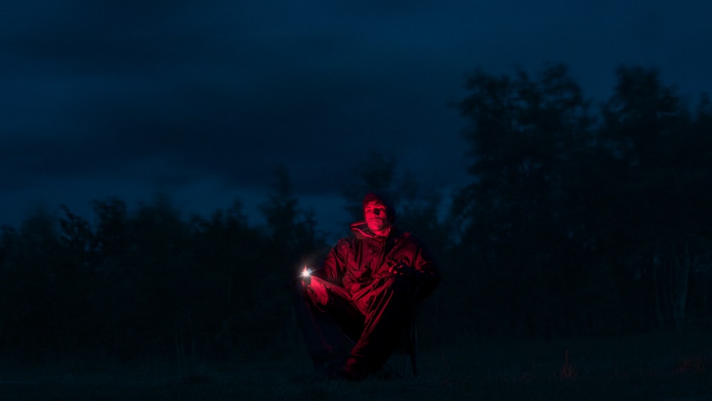 a man sitting in the dark holding a flashlight