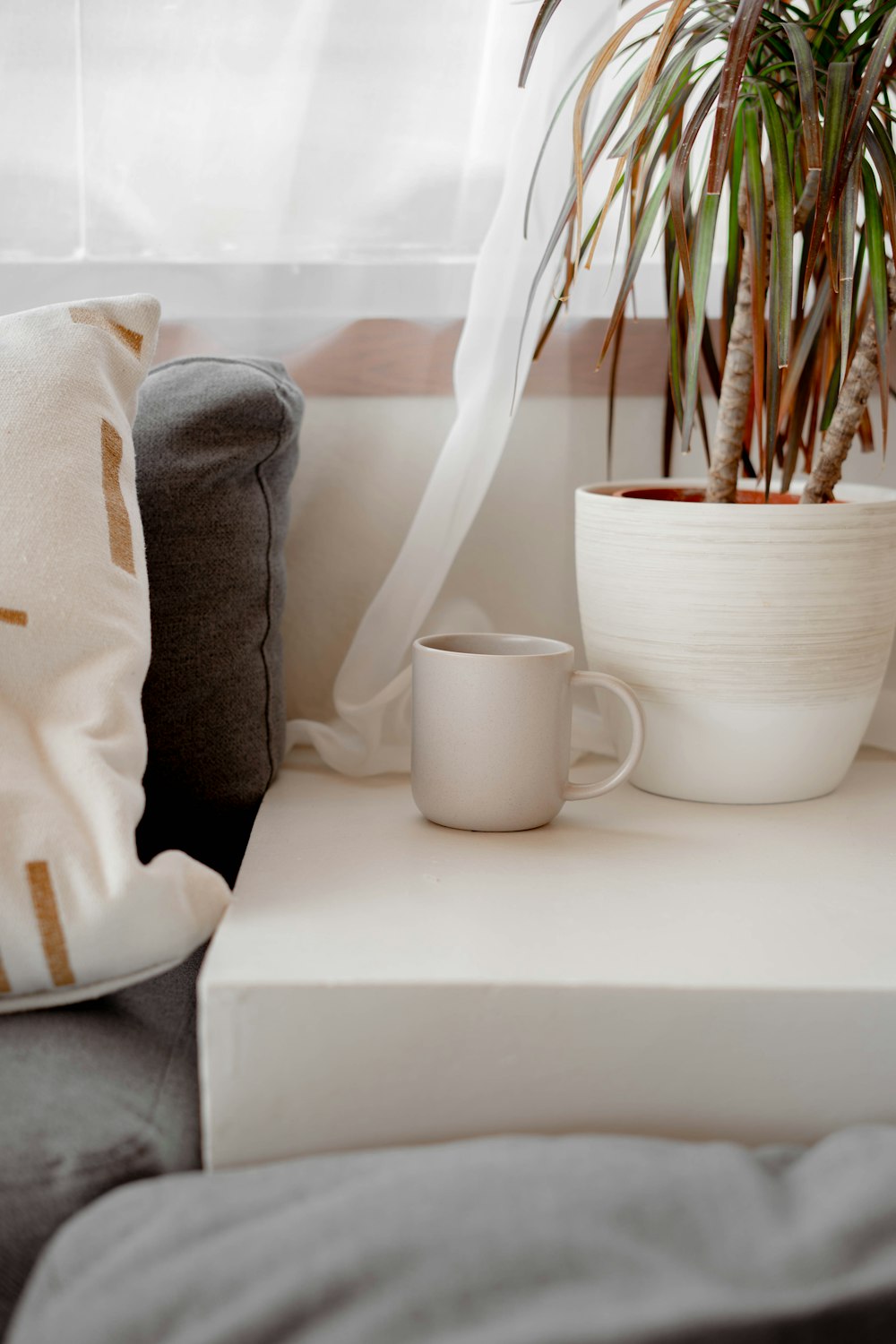 a coffee cup sitting on a table next to a potted plant