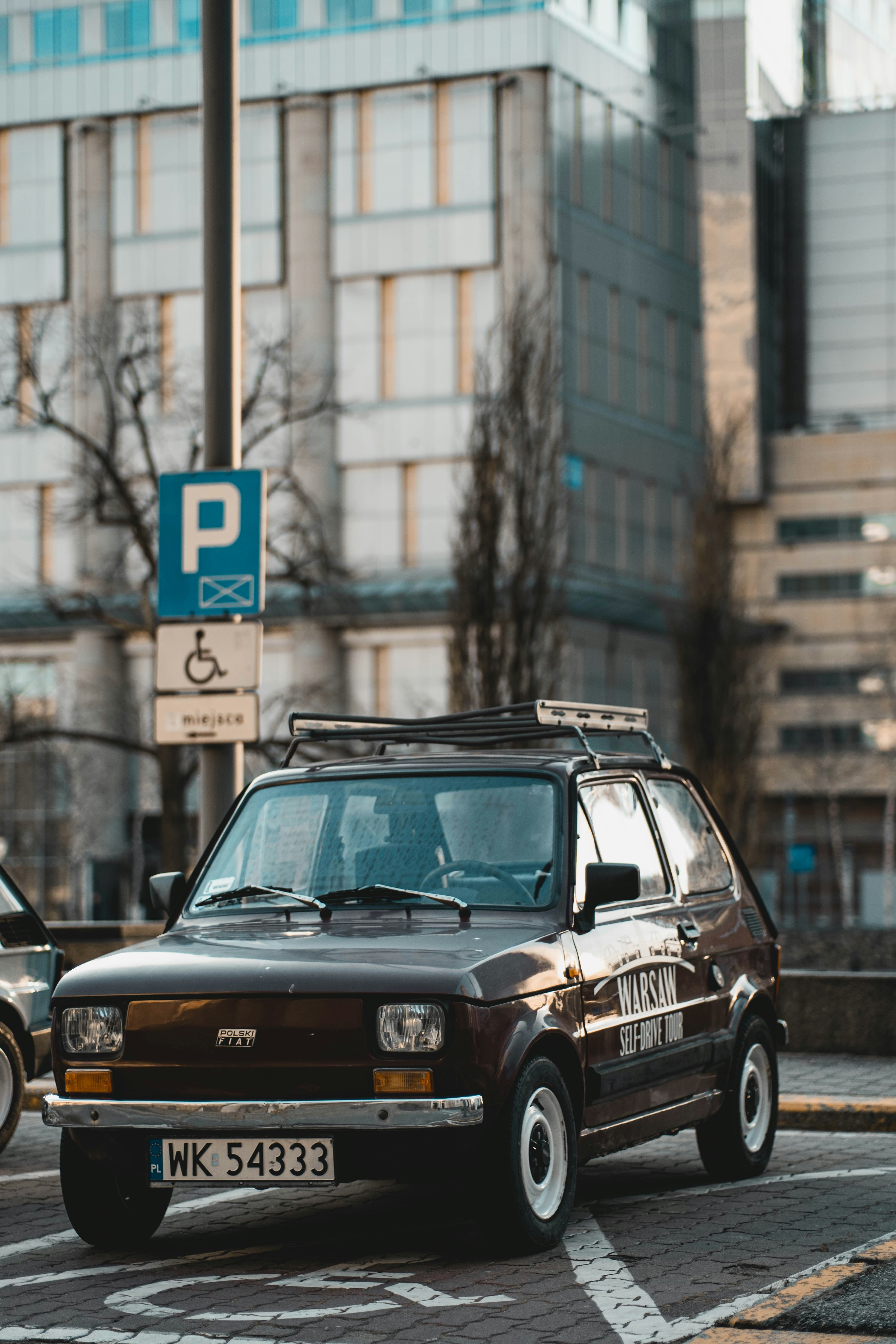 a brown car driving down a street next to a tall building