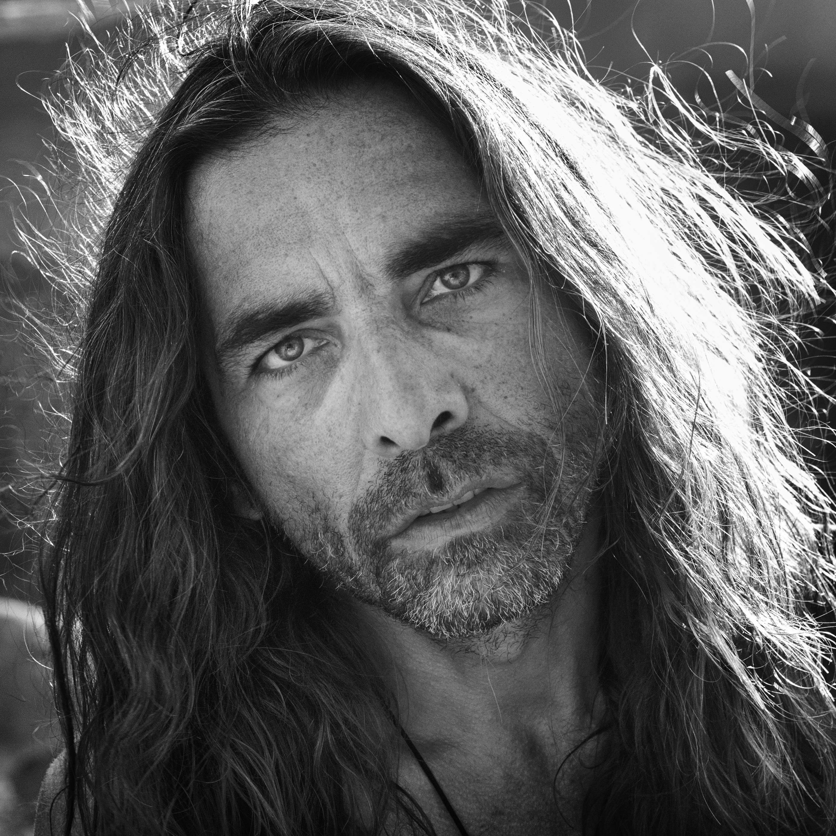 a black and white photo of a man with long hair