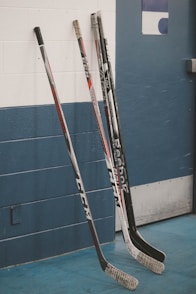 two hockey sticks leaning against a wall in a gym