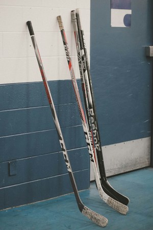 Hockey sticks leaning against a wall inside a rink between practice sessions