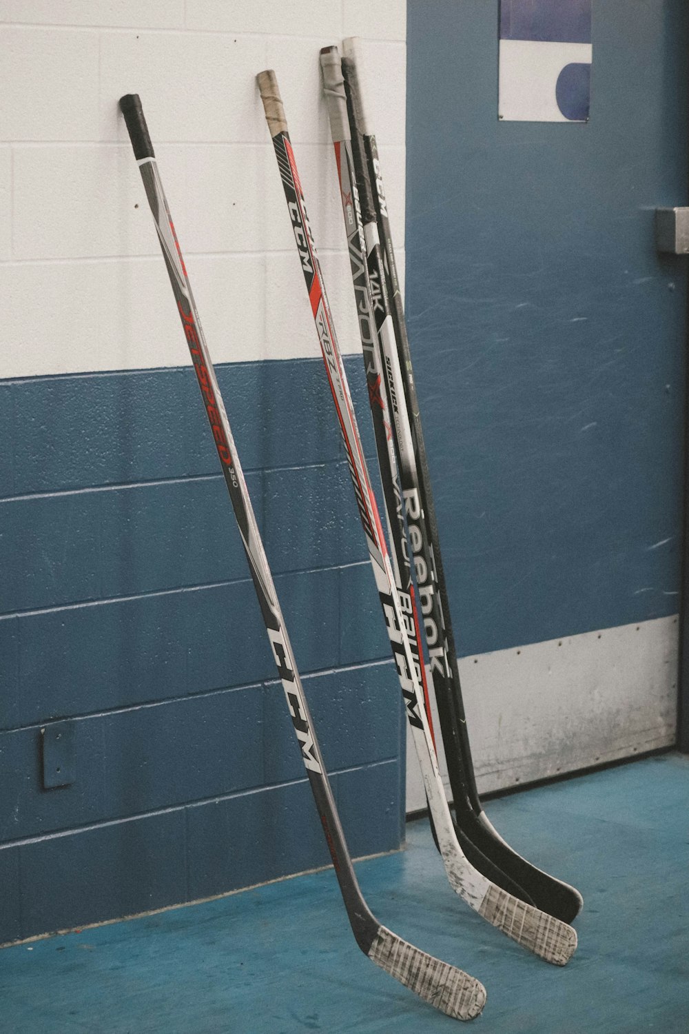 two hockey sticks leaning against a wall in a gym