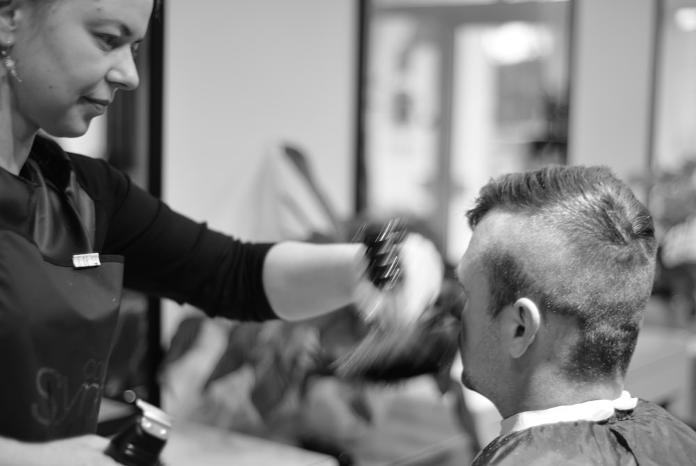 a woman cutting a man's hair in a salon