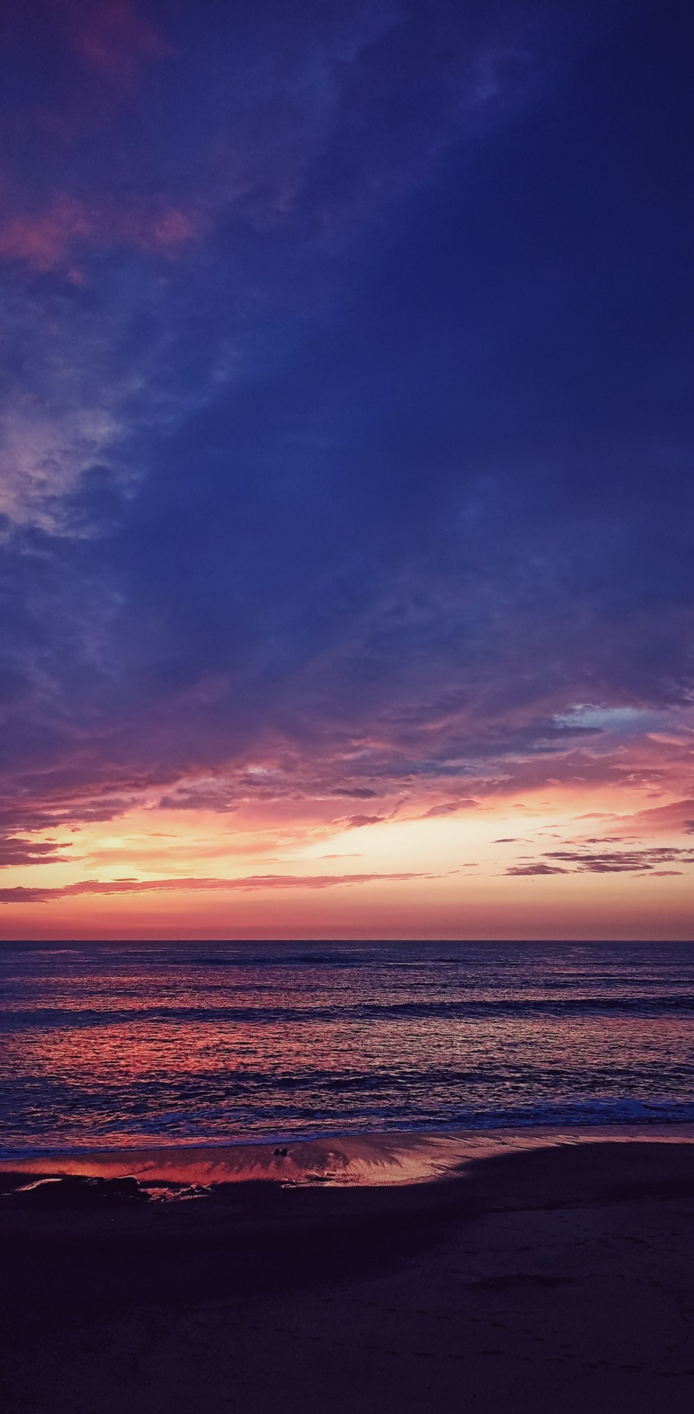 a person walking on the beach at sunset