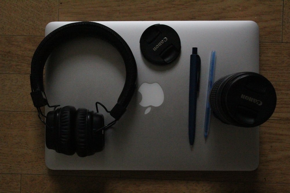 an apple laptop with headphones, a pen, and a pair of headphones