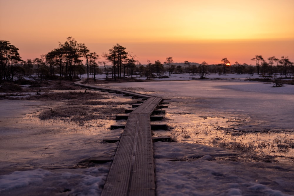 a long wooden walkway in the middle of a snow covered field