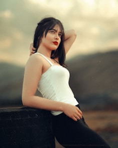 a woman in a white top leaning on a wall