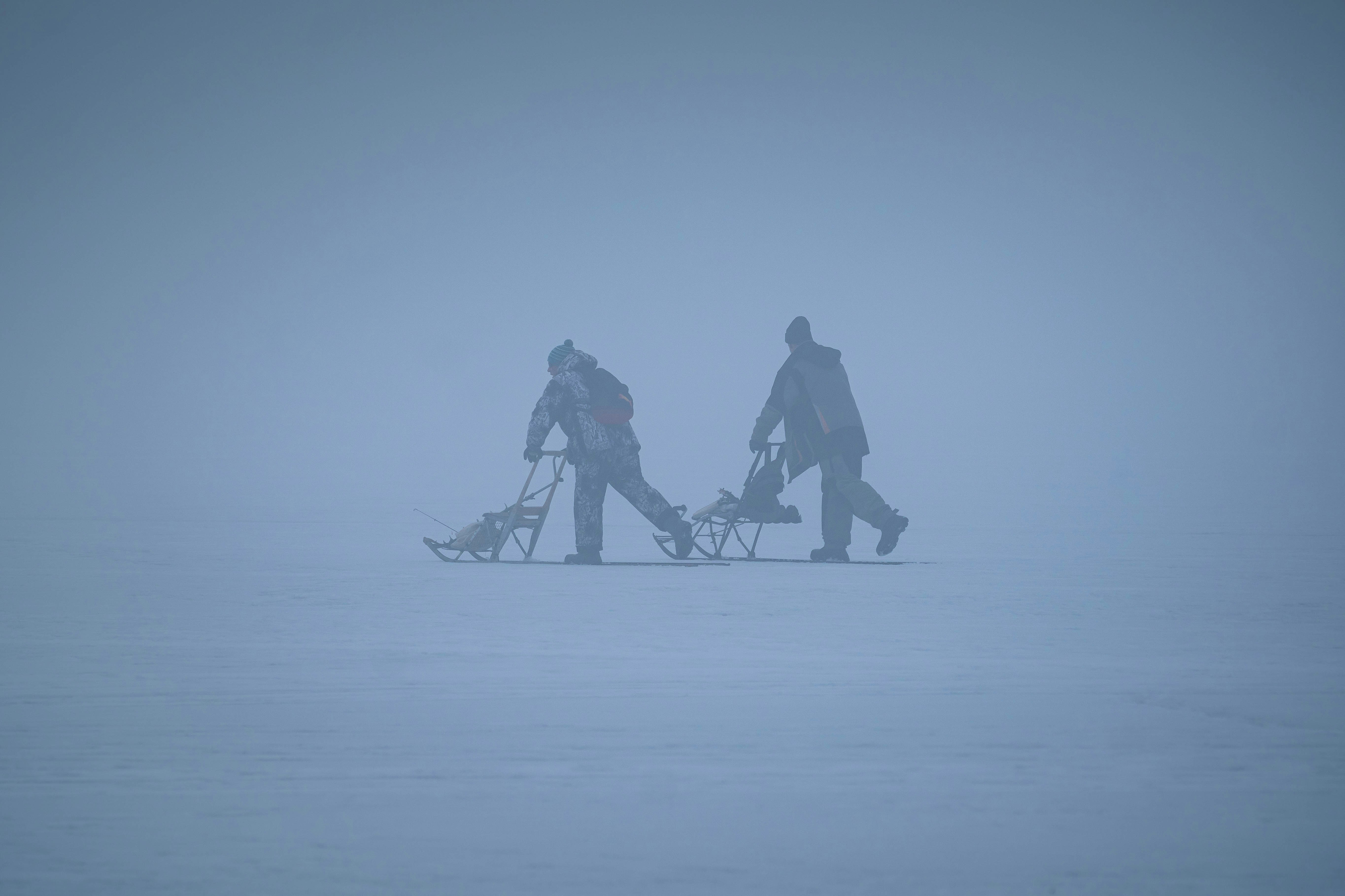 a couple of people walking across a snow covered field