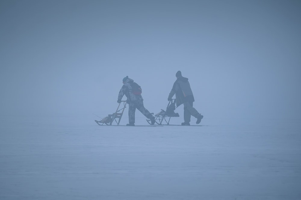 a couple of people walking across a snow covered field