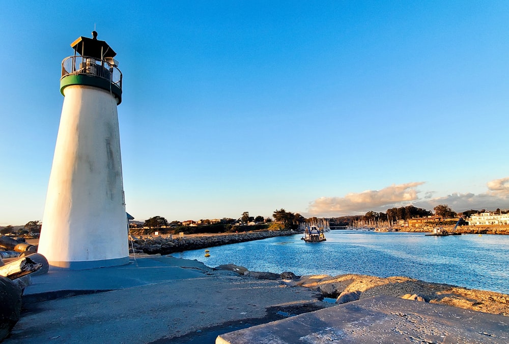 a white and black light house next to a body of water