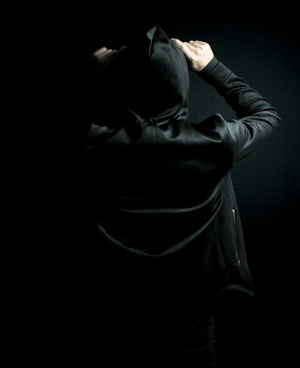 a person in a black hoodie standing in the dark