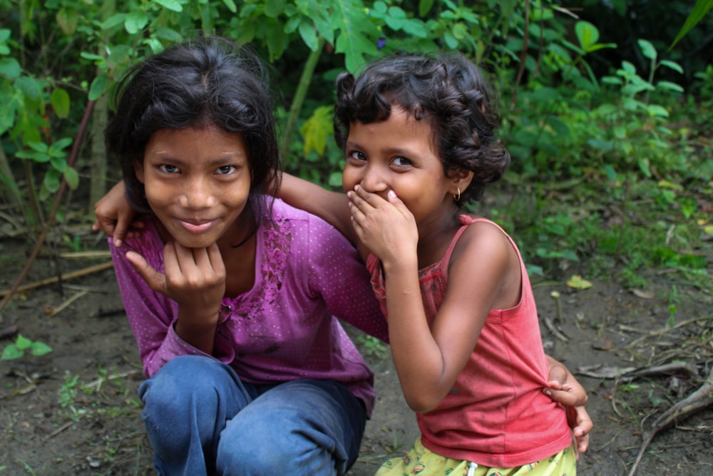 two young girls sitting on the ground with their hands together