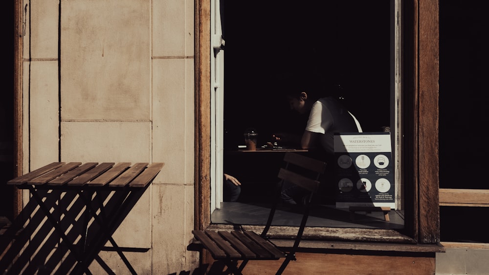 a couple of wooden chairs sitting outside of a window