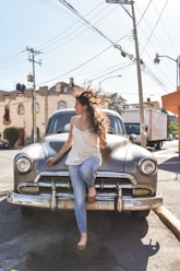 a woman sitting on the hood of an old car