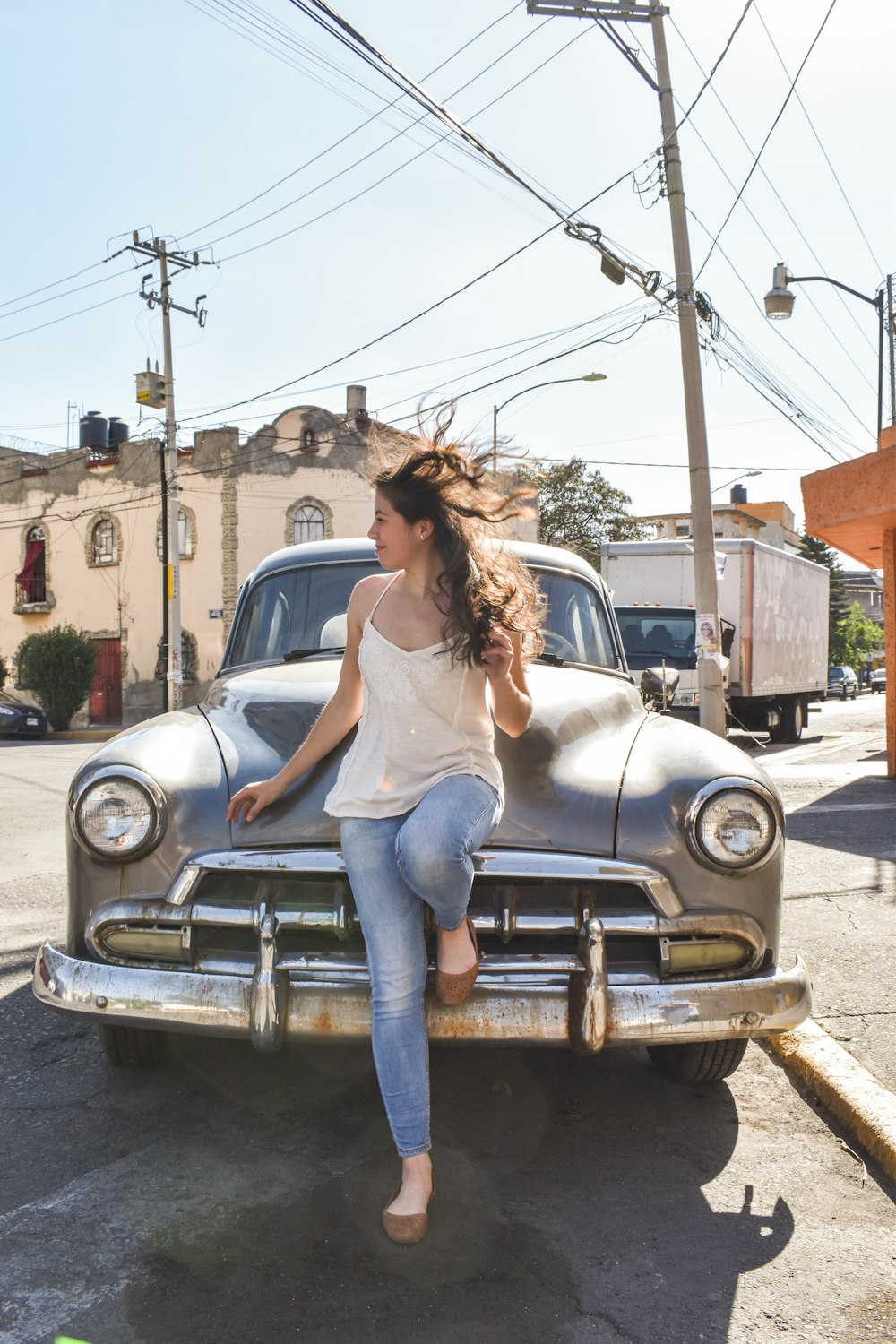 a woman sitting on the hood of an old car