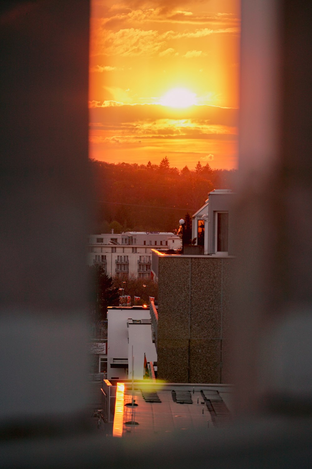 the sun is setting over a city from a window