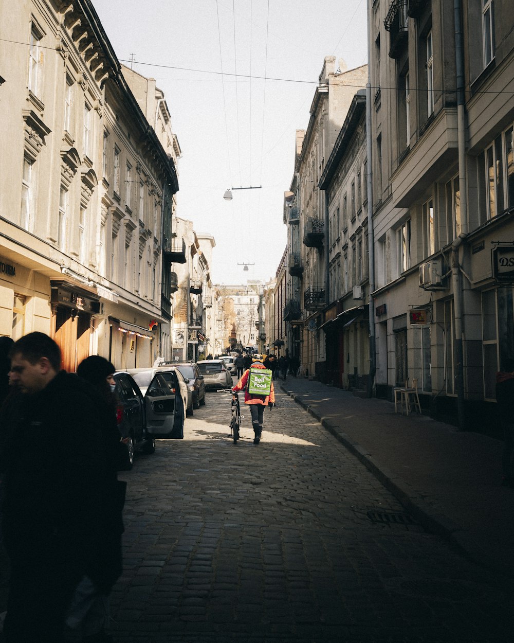 a man walking down a street next to tall buildings