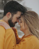 A candid shot of a couple sharing a moment, both dressed in cozy vestawear sweaters.